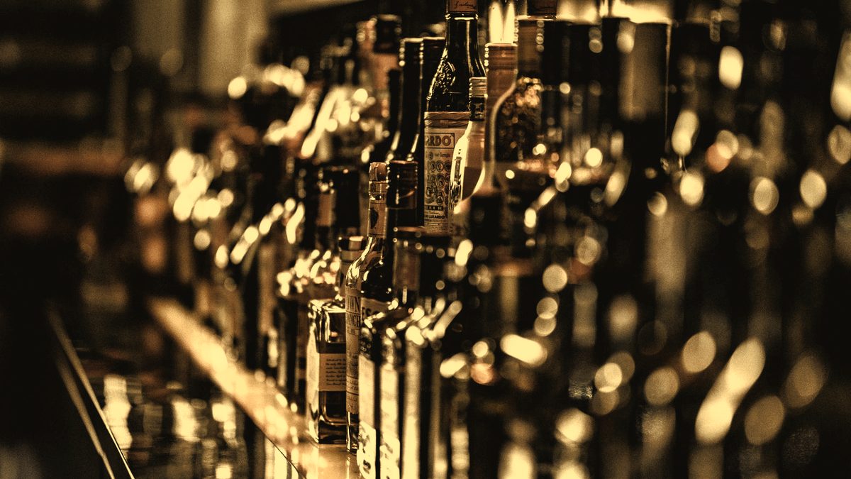 A shelf of whiskey bottles in low amber light, the labels soft and out of focus